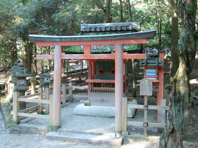 A red torii in front of a red sanctuary building