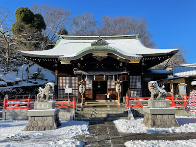 A snow-capped jinja prayer hall, with koma-inu in front.