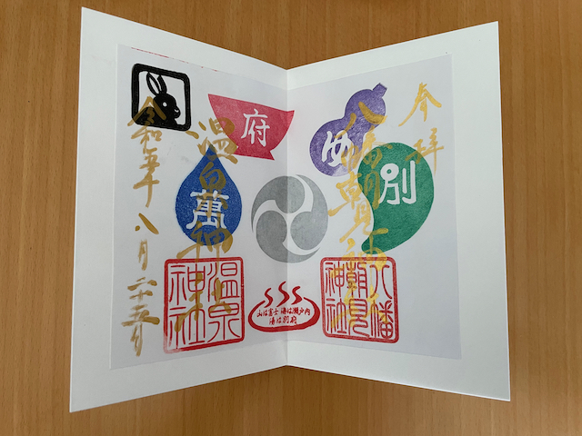 One special annual goshuin. The writing is in gold, and there are multicoloured stamps of items and Japanese characters associated with the jinja.